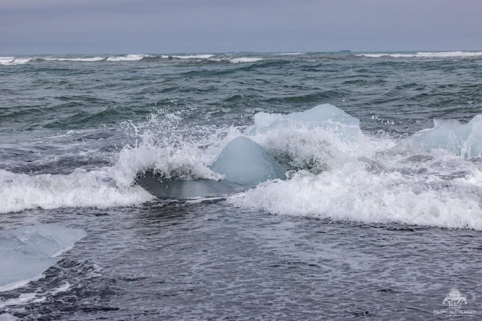 Surf washing over stranded ice on Diamond Beach's black sand