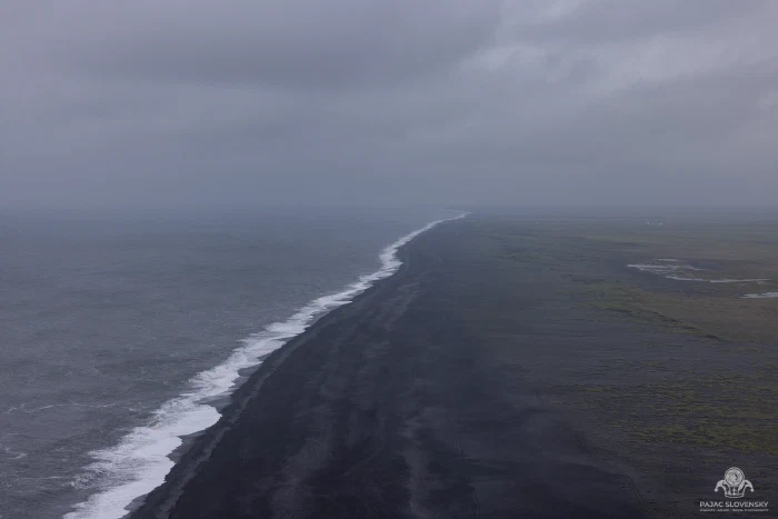 Endless black sand beach and surf line from Dyrholaey clifftop, overcast