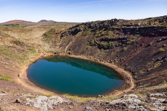 Aquamarine lake filling Kerið volcanic crater's red-walled caldera