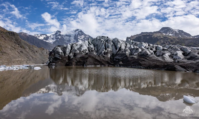 Serac wall of a glacier tongue mirrored in still lagoon water
