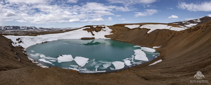 Turquoise Viti crater lake at Krafla ringed by snow patches