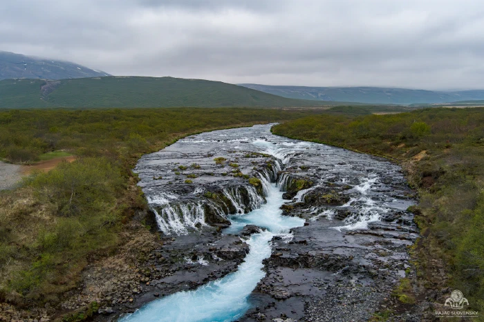 Brúarfoss waterfall, turquoise cascades converging into a dark lava channel