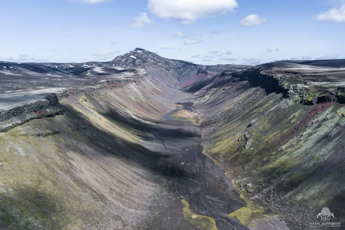 Aerial down Eldgja fissure: maroon-green slopes, black braided valley floor