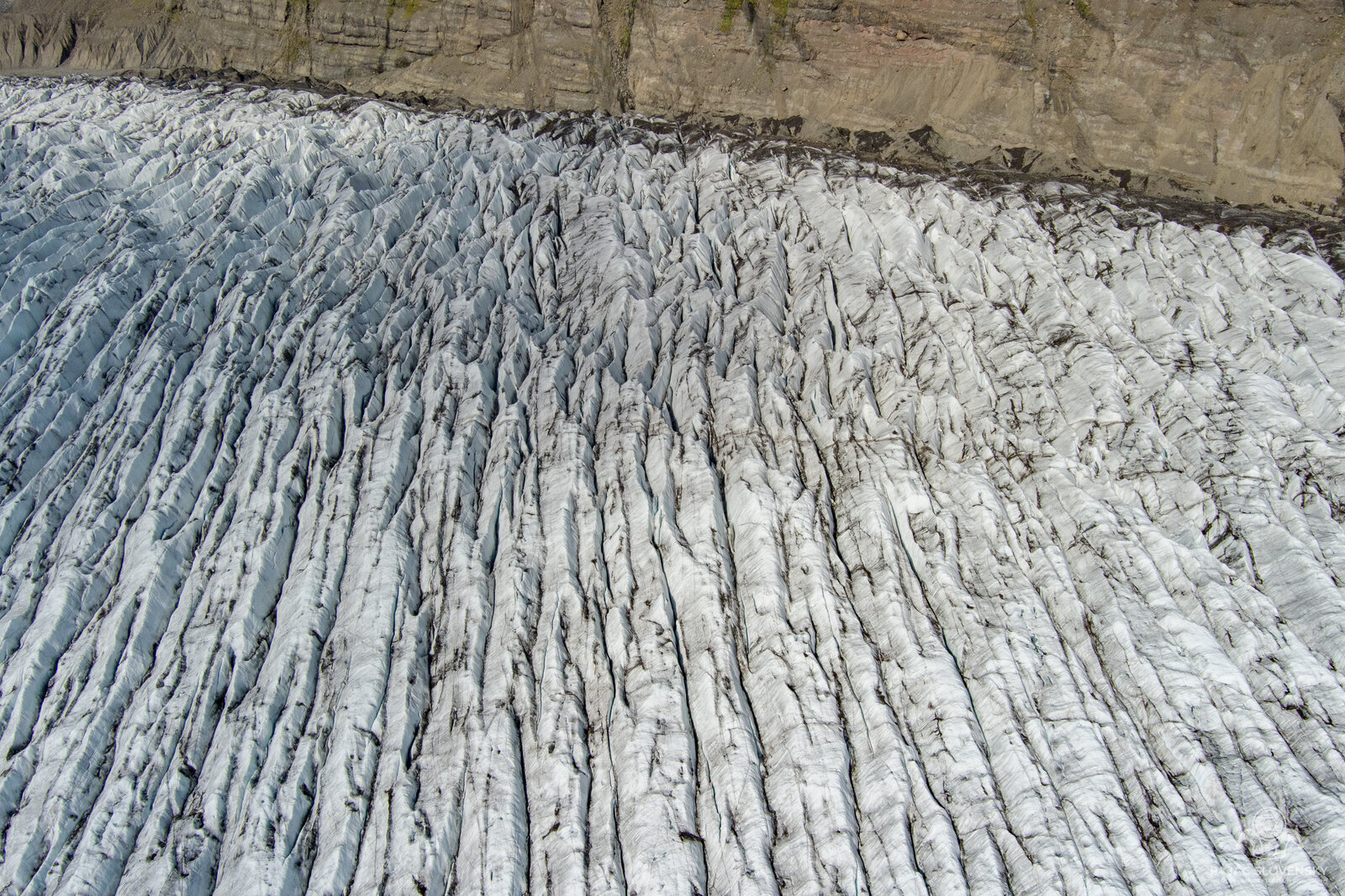Parallel crevasse ridges meeting the brown moraine wall from above