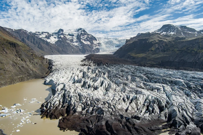 Aerial of a crevassed glacier tongue descending toward a meltwater lagoon