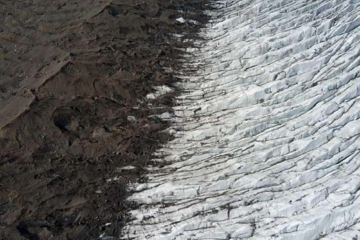 Top-down divide between brown moraine debris and white rippled ice