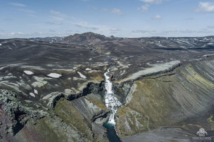 High aerial of Ofaerufoss threading a dark fissure in black highlands