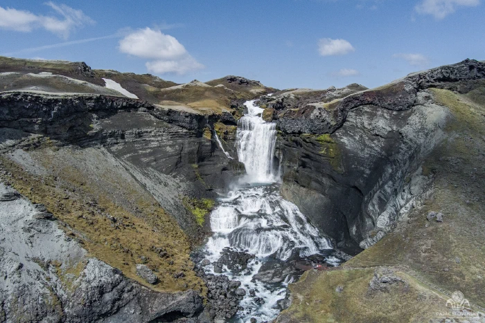 Two-tiered Ofaerufoss waterfall plunging through dark Eldgja volcanic canyon