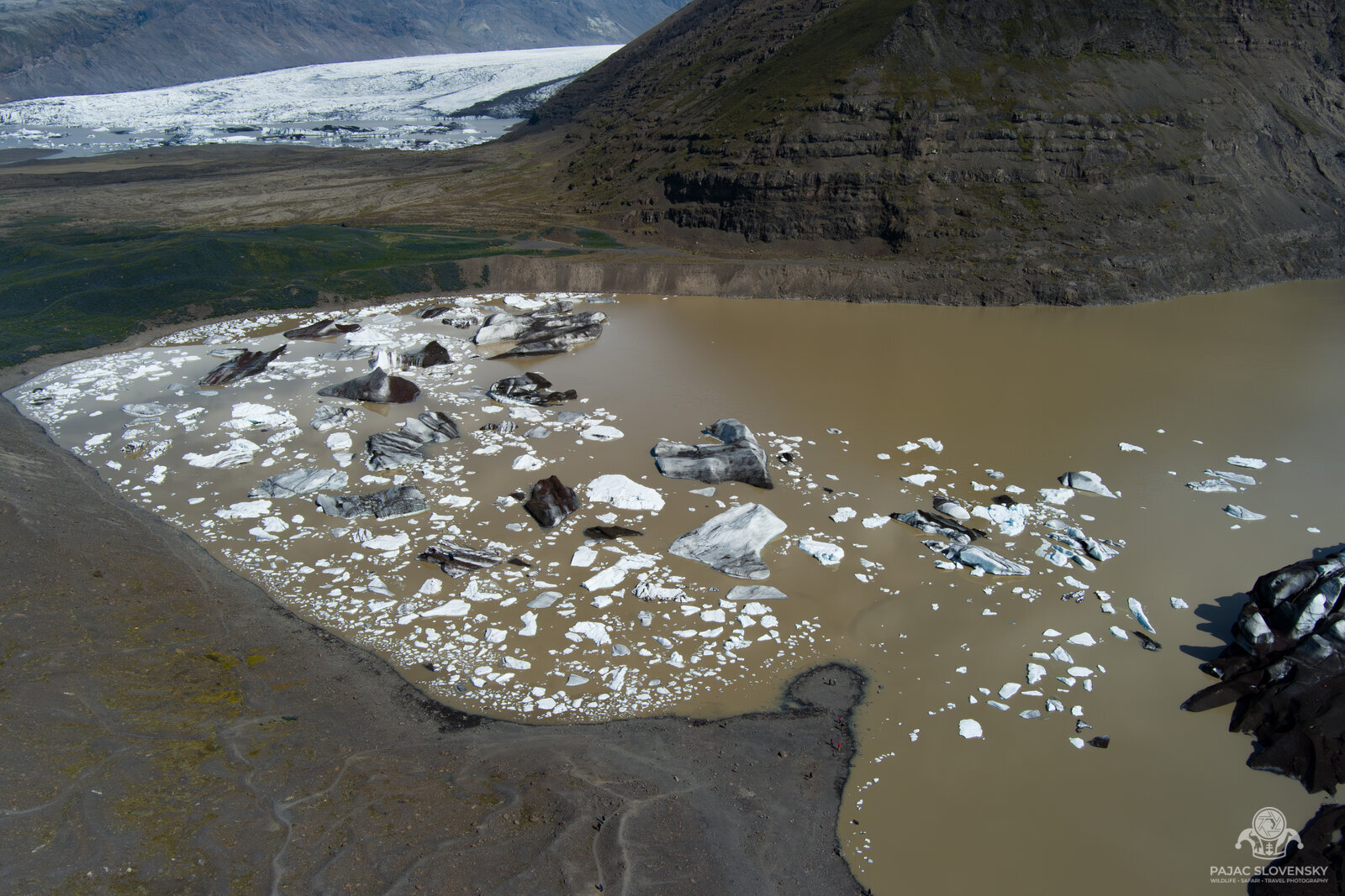 Striped icebergs on the muddy lagoon at the glacier snout, seen from above