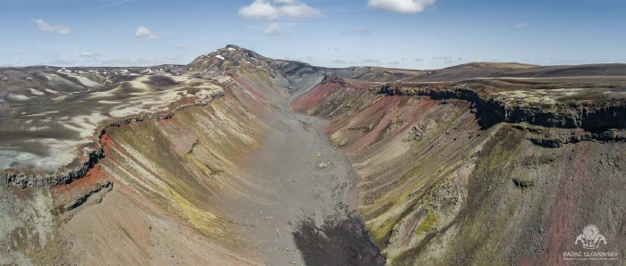 Aerial panorama of volcanic canyon with red, ochre and green striped walls