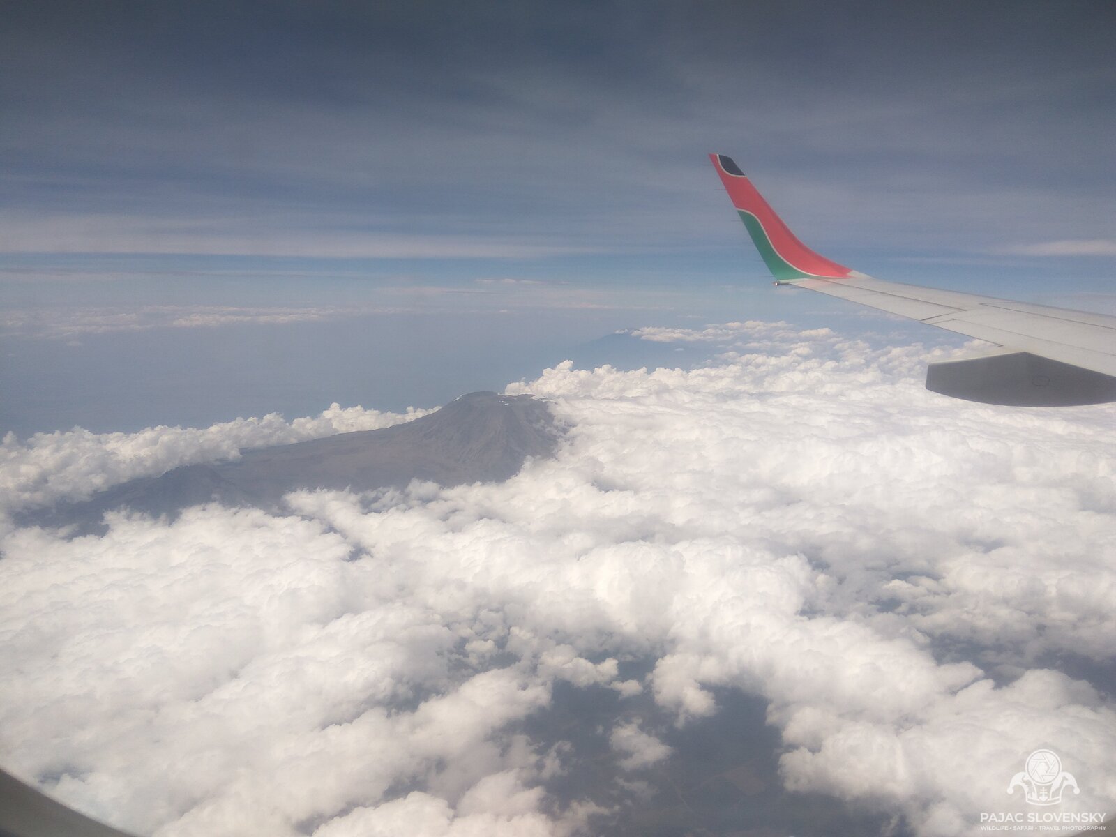 Kilimanjaro rising above the clouds, seen past the aircraft wing on the flight home