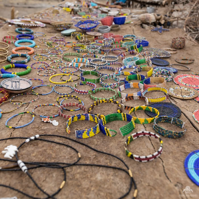 Colorful Maasai beaded bracelets and necklaces displayed on dry ground
