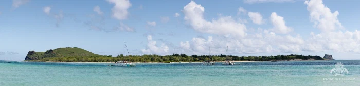 Sea-level panorama of the Flat Island lagoon with moored catamarans