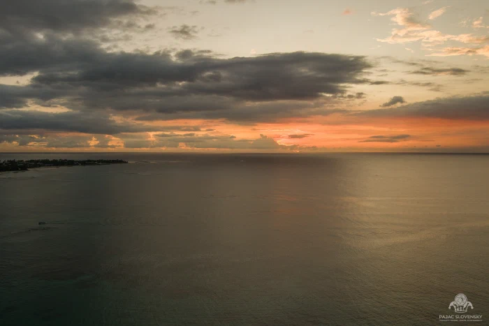 Aerial of sunset over the Indian Ocean beneath a shelf of dark cloud