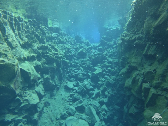 Boulder-strewn floor of the Silfra fissure under pale blue-green water