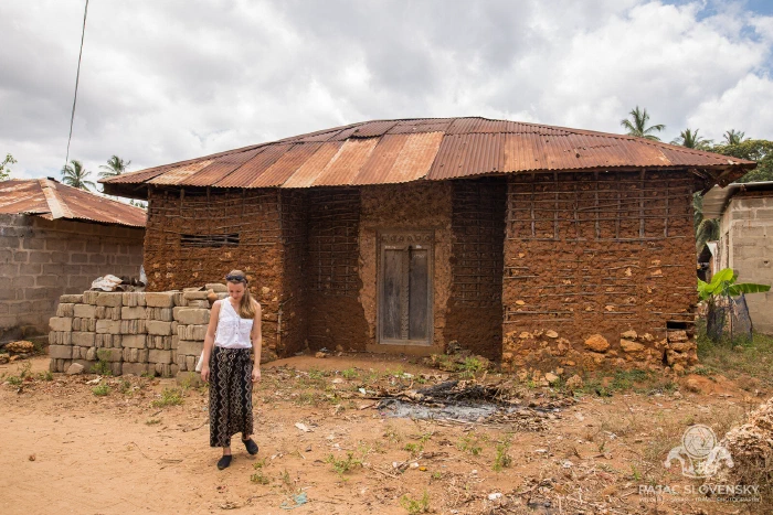 A villager at the door of a house with a rust-red roof