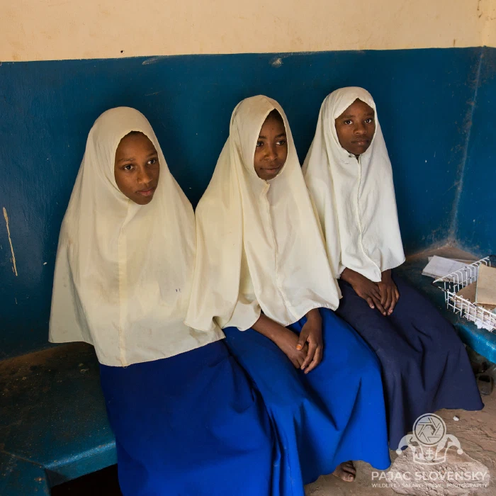 Schoolgirls in white hijabs and blue uniforms at their bench