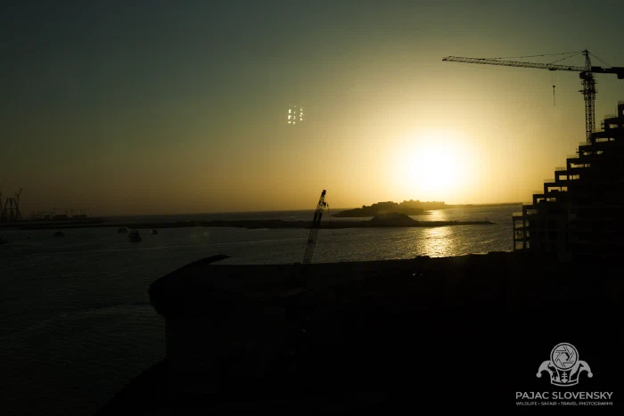The sun dropping into the sea beyond the harbour