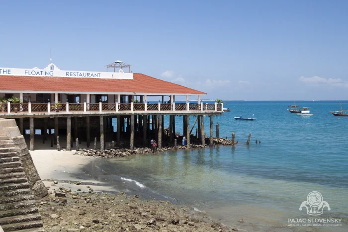 Red-roofed waterfront restaurant standing over the shallows